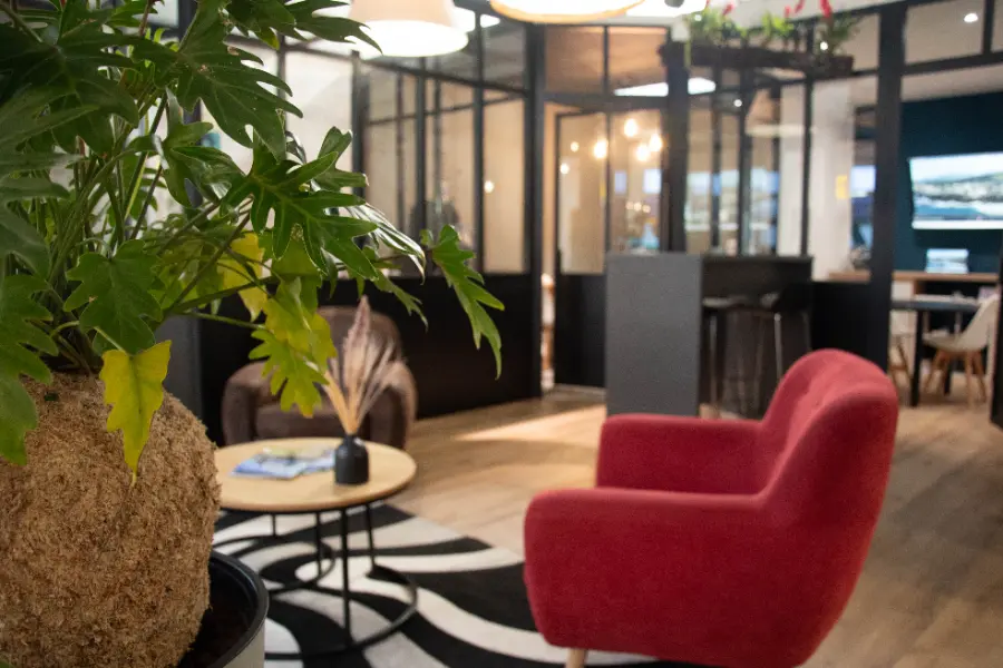 L'intérieur de l'agence de Saint-Pierre : un fauteuil rouge, des plantes et des bureaux vitrés